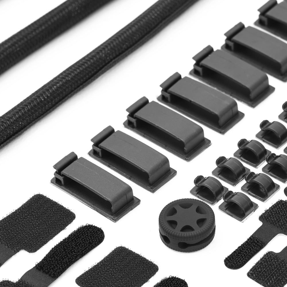 A close-up of black cable management accessories from the Cable Management Kit, including clips, sleeves, adhesive holders, Velcro straps, and a round desk piece, all neatly arranged on a white background for efficient cable organization.
