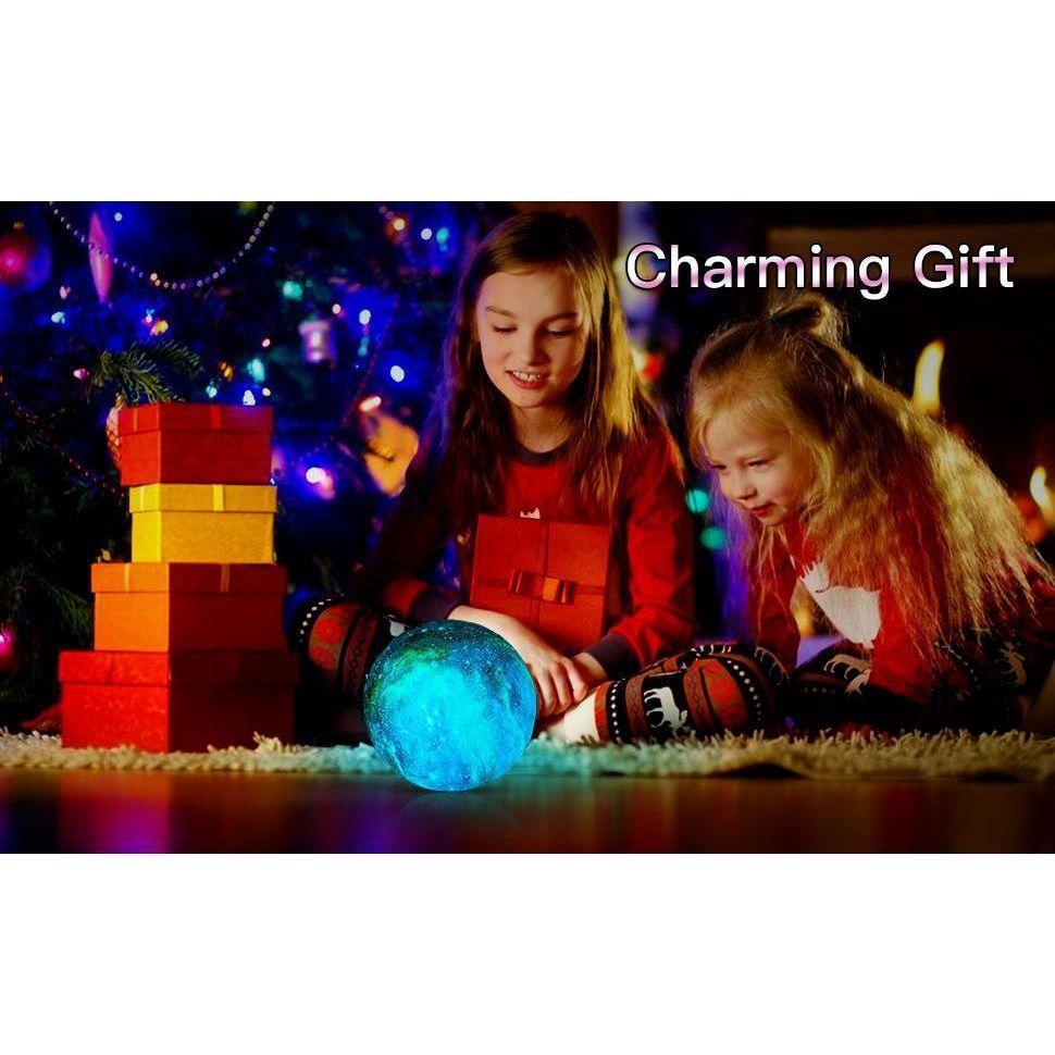 Two children sit by a Christmas tree with colorful lights, surrounded by gifts. They are captivated by a glowing blue orb similar to the Celestial 3D Moon Lamp LED Night Light. The words Enchanting Starry Decor Gift are in the top right corner.