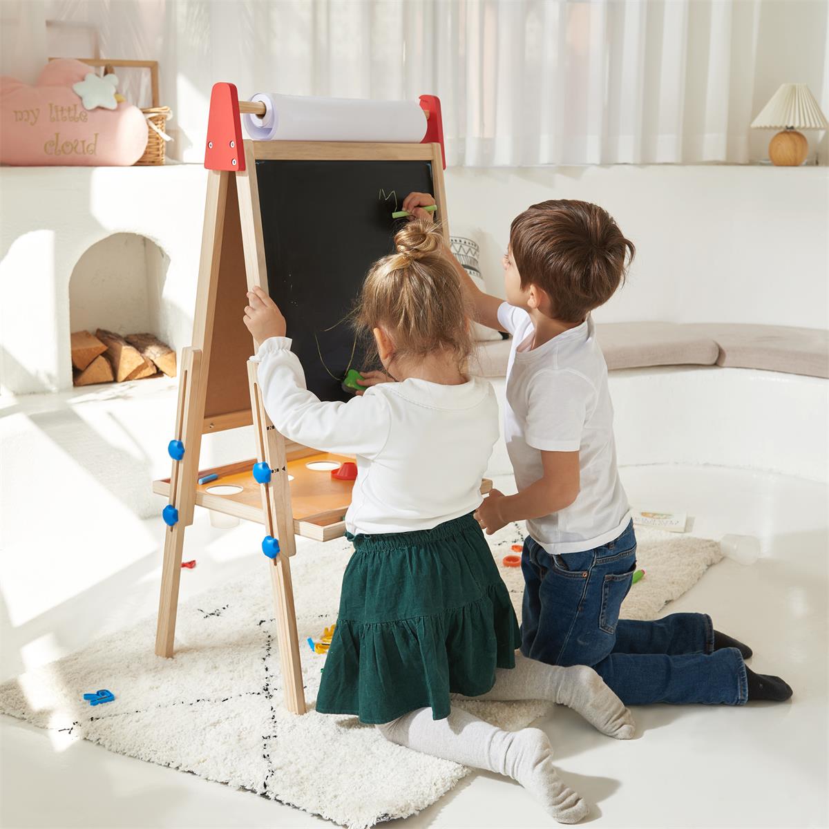 Two young children kneel on a rug and draw on the Tiny Land® 3-in-1 Art Easel for Kids in a bright, cozy room filled with natural light, toys on the floor, and a “my little cloud” pillow in the background.