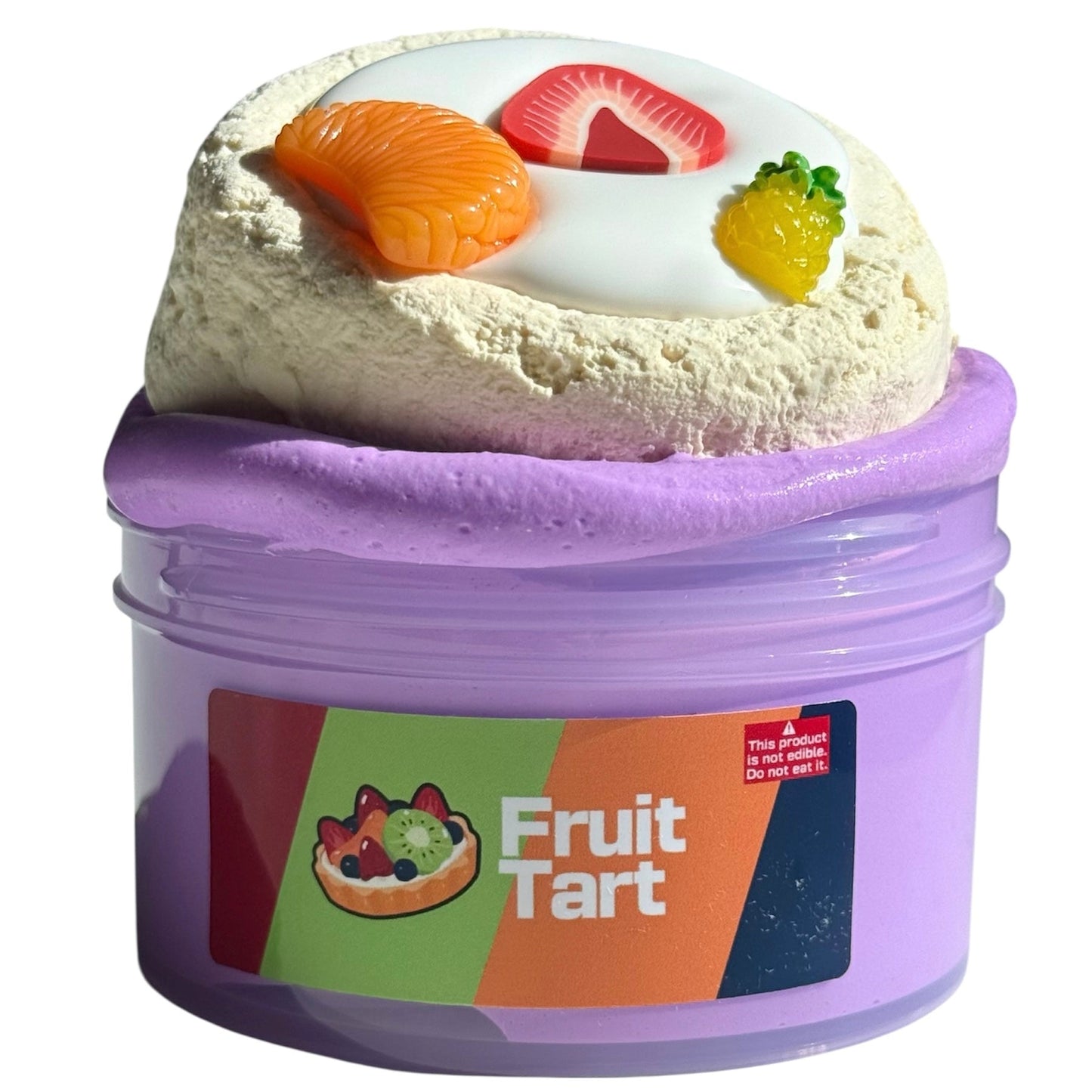 A purple cup labeled Fruit Tart DIY Clay Slime contains 7 oz of fruit smoothie-scented purple slime with a white center, a tart decoration, and three random fruit charms. Warning: This is not food. Do not eat it.