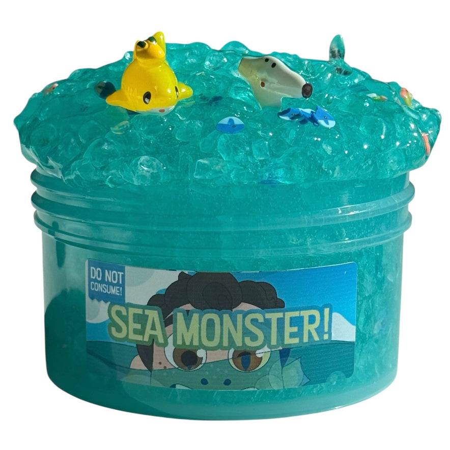 Sea Monster Teal Silica Slime (7 oz) features rainbow sherbet scent, a random fish charm, and comes in a clear container with "SEA MONSTER! DO NOT CONSUME!" label—perfect for sensory play and collecting.