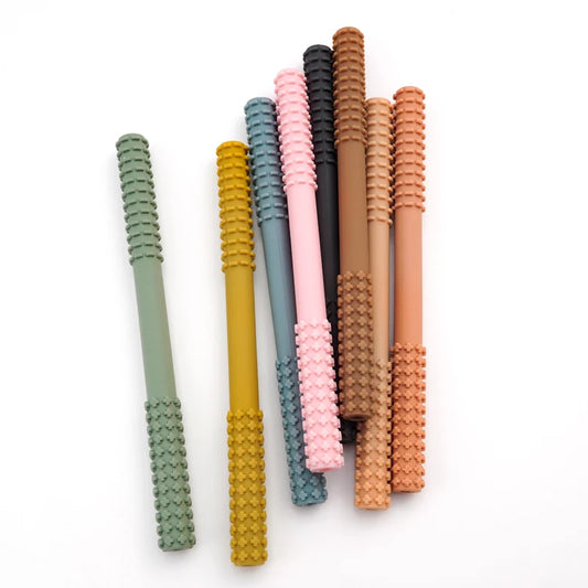 The Essential Tiny Teething Toy for Infants, made of textured silicone for oral protection, comes in pastel green, yellow, pink, and brown. These straws are arranged semi-circularly on a white background to highlight their appeal for baby health through safe chewing and fidget fun.