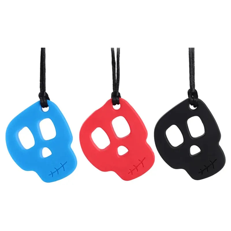 The Silicone Skull Teething Necklace for Babies, in blue, red, and black on black cords, features skull-shaped teethers with eye and nose cutouts plus stitched details. Perfect for teething relief on a plain white background.