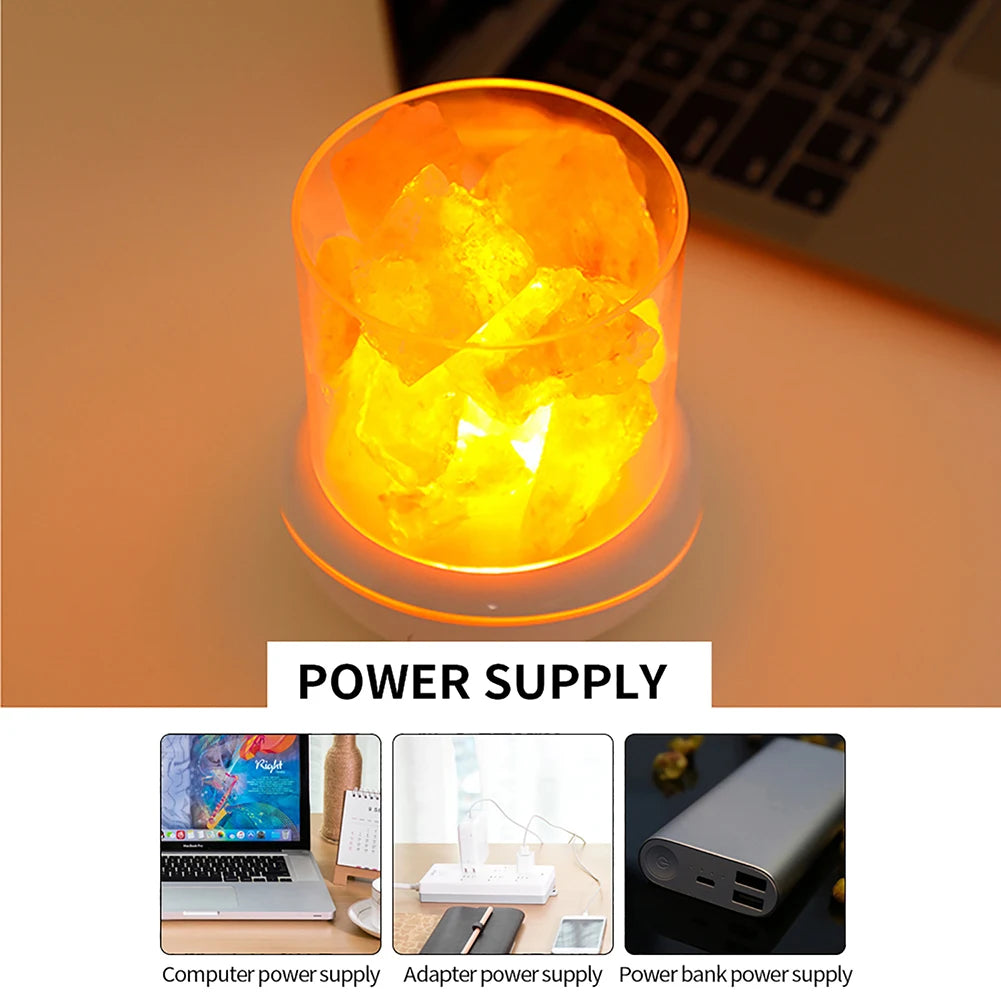 The Crystal Salt Lamp with USB Aroma Purifier & LED Multicolor Night Light emits an orange glow beside a laptop. Three images display power supply options: computer USB, power adapter, and power bank, labeled as Power Supply.