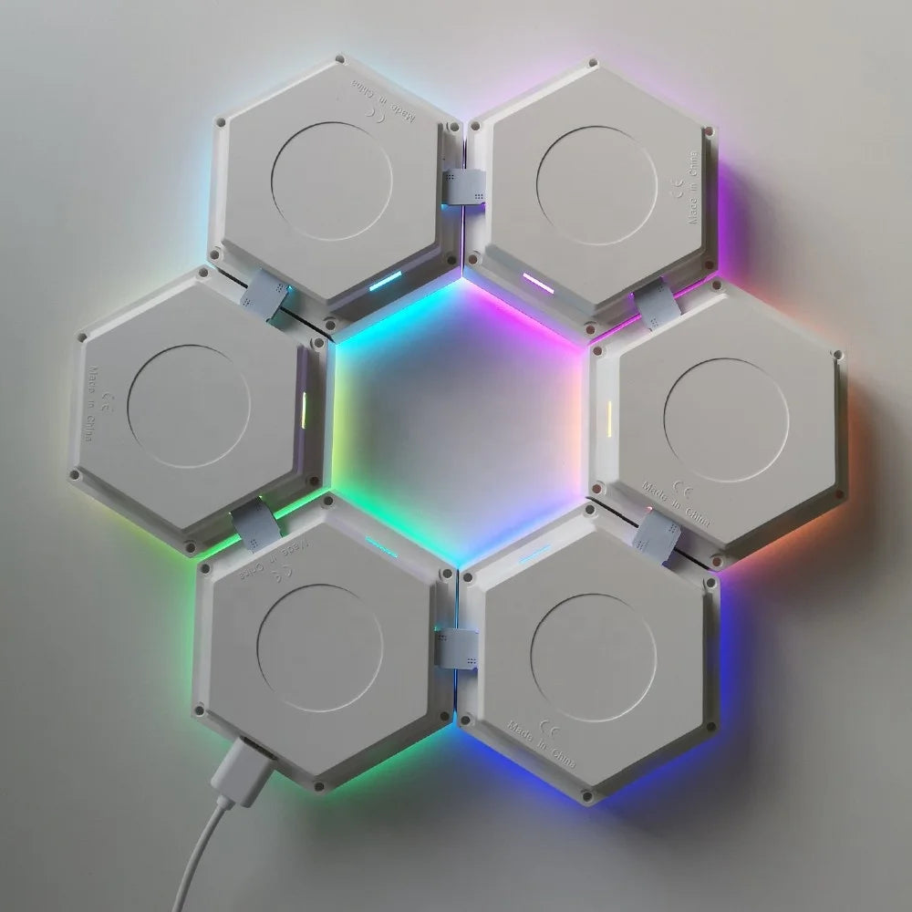 The Modular Hexagonal LED Wall Panels create a stunning rainbow effect with each glowing in different colors. Mounted on a white wall, this night light has a power cable to one module and is easily controlled via remote, offering sensory support and a calming ambiance.