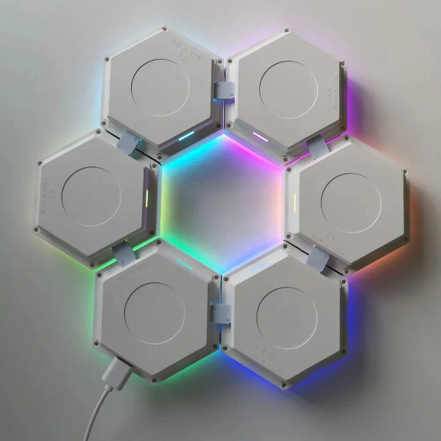 Six Hexagonal LED Modular Night Light Panels for Sensory Rooms are joined edge-to-edge in a circular pattern, glowing softly with color-changing lights. One panel connects to a power cable, creating a calming, versatile night light for autism support.