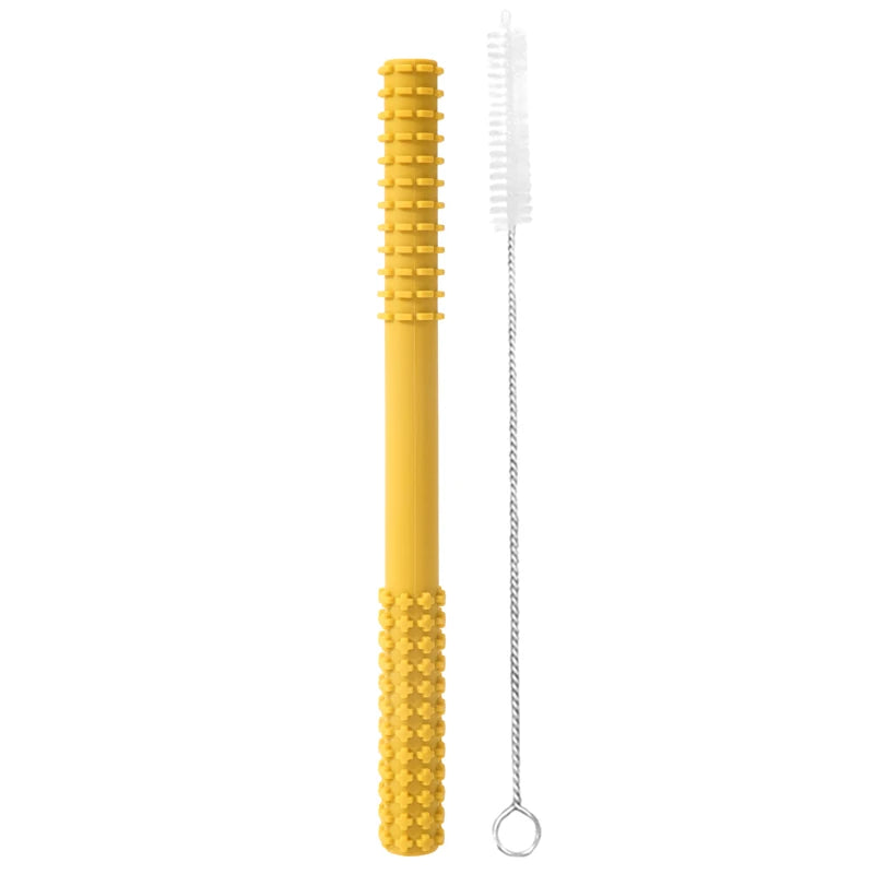 A 005-mstard tiny teething toy, perfect for infants, with a textured grip and cylindrical design featuring raised bumps for healthy development, sits beside a white slender cleaning brush with a spiral handle, ideal for narrow objects.