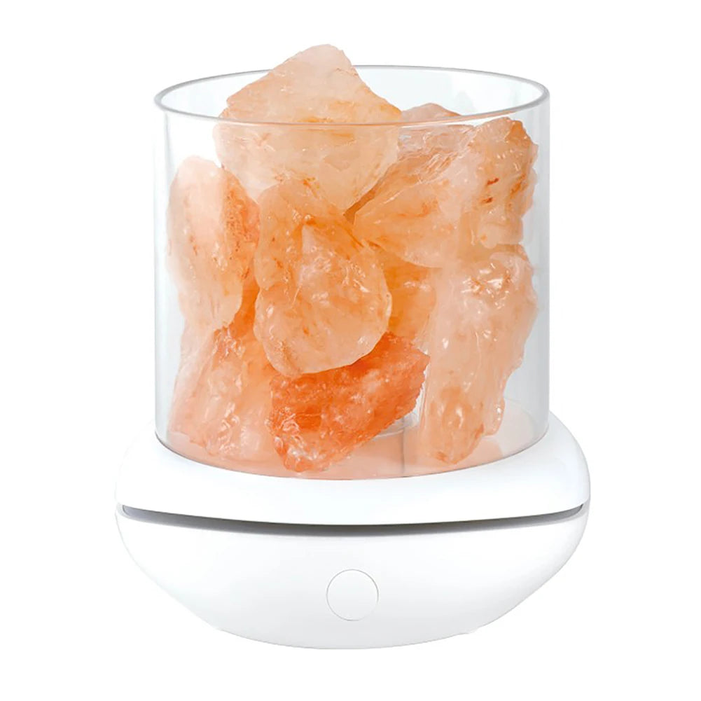 The Crystal Salt Lamp with USB Aroma Purifier features a clear glass container holding large Himalayan salt crystals on a white base. The base has a button that activates the LED Multicolor Night Light, while the varied shapes of the salt add charm to this unique lamp for serene bedrooms.