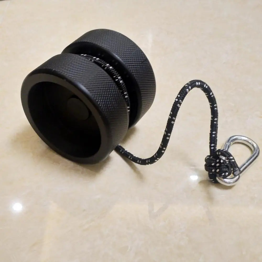 The Finger Grip and Forearm Strength Trainer - Anti-Slip Wrist Impact Tool, a black yoyo with a knurled texture for an anti-slip grip, sits on a smooth, light surface. It features a black and white speckled string with a small loop and metallic clip.