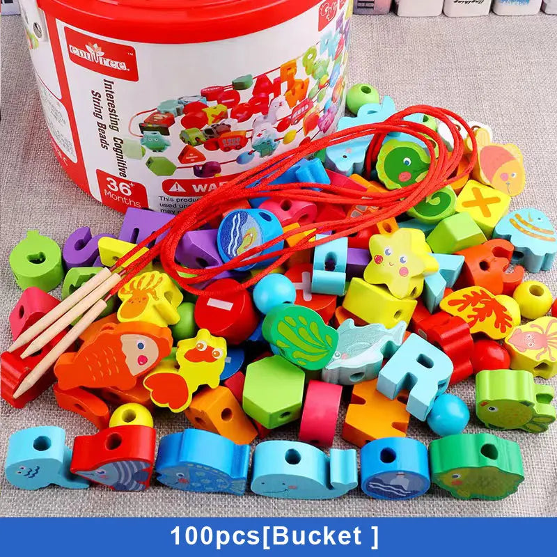 A variety of wooden beads, featuring letters, animals, and shapes, are scattered before a red and white bucket. These safe educational toys include a red string and wooden sticks for threading fun. Product: Wooden Beaded Toys Fruits Vegetables Animal Traffic Blocks Beads Toys; Color: 100PCS Bucket A.