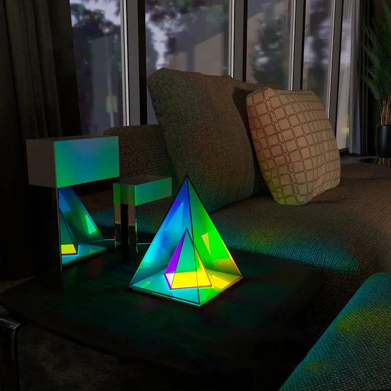 A Vibrant RGB LED Night Light for Parties and Home Décor is placed on a dark table next to a modern sofa, casting dynamic colors across the dimly lit room with large windows for a stunning light display.