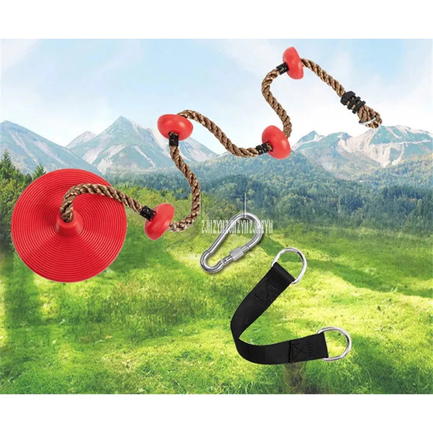 The Outdoor Adventure Climbing Ropes for Kids is a vibrant red disc swing with brown braided rope, red knots, and a metal carabiner paired with a black strap, set on green grass against mountains and blue sky, ideal for sensory play and promoting childrens physical development.