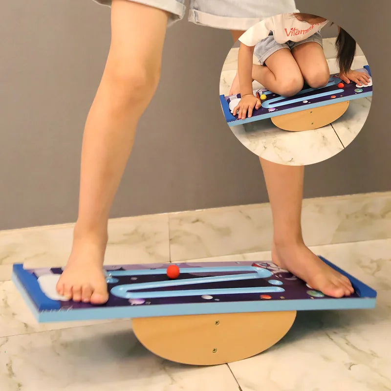 A child balances barefoot on a Kids Wooden Balance Board, featuring a maze, tilting on a semi-circular base for sensory training. An inset shows the child crouching, focused on maneuvering a red ball through the maze during their physical activity.