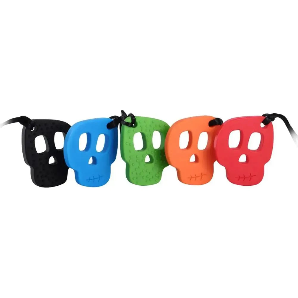 Five Silicone Skull Teething Necklaces for babies, perfect as sensory chewy toys for autism and ADHD, are lined up in black, blue, green, orange, and red. Each pendant features eye and nose holes with small mouth indentations and hangs on black strings against a white background.