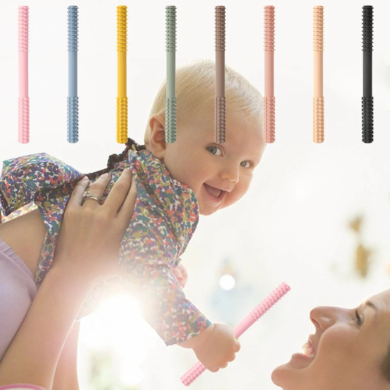 A smiling baby in a colorful outfit is lifted high by a beaming adult, surrounded by vibrant textured rods that evoke the joy of using the Essential Tiny Teething Toy for Infants—perfect for safe chewing and promoting healthy development.