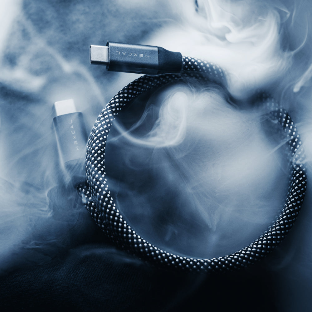 A Magnetic Charging Cable, braided and coiled on a surface, is surrounded by wisps of smoke or mist, illuminated with a cool blue-toned lighting effect.