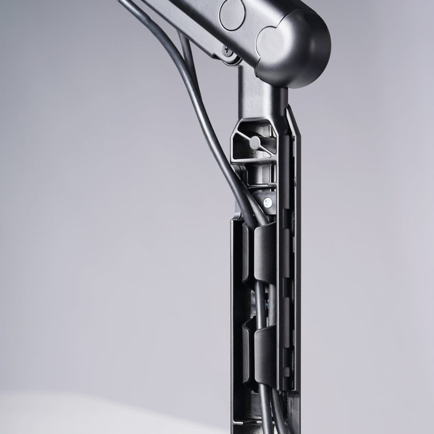 Close-up of a Single Monitor Arm with an integrated cable management system, neatly organizing black cables against a light gray background for an ergonomic workspace.