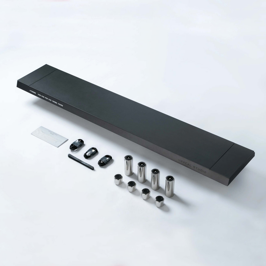 A black rectangular Hexcal Studio™ with AI COCA STUDIO branding, four metal cylinders, four black adapters, a pen-like tool, a card, and a small white item are neatly arranged—ideal for cable management or workstation organization.
