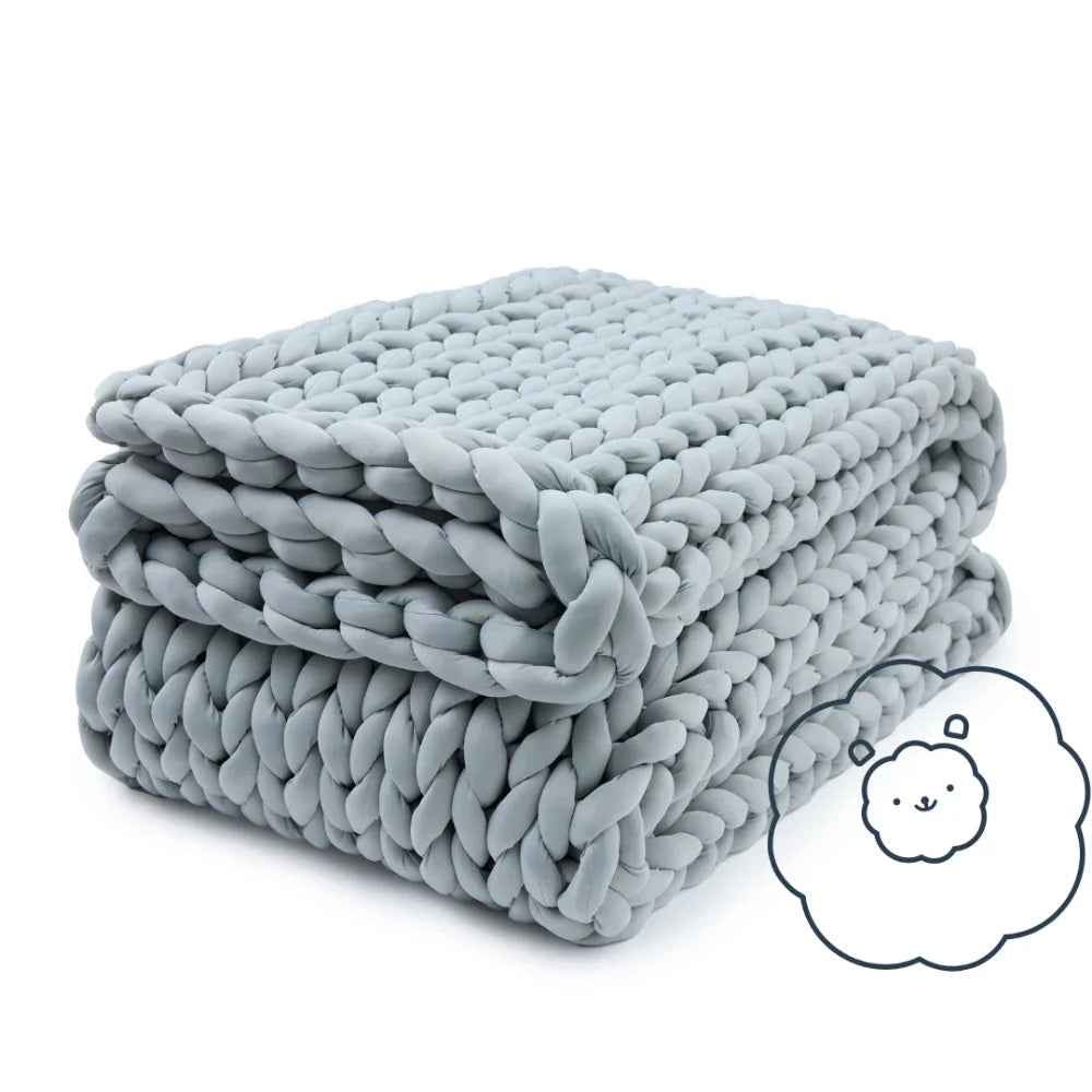 A neatly folded, thick light gray Ice Knit Weighted Blanket features a small illustration of a smiling cloud inside a thought bubble in the bottom right corner.
