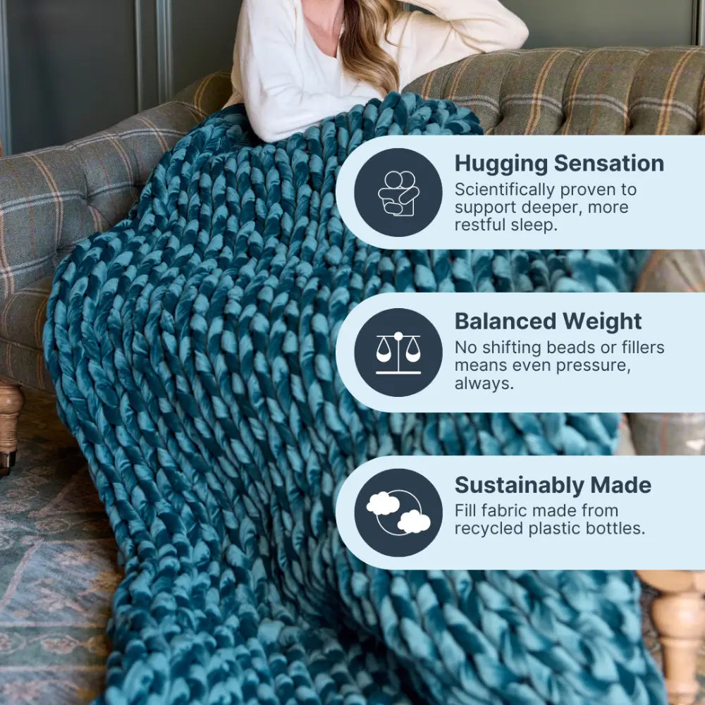 A woman relaxes on a couch wrapped in the Velvet Weighted Blanket, enjoying its hugging sensation, cozy comfort, balanced weight, and eco-friendly fill crafted from recycled plastic bottles.