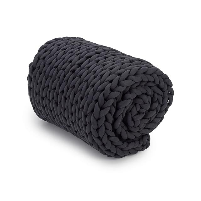 The Knit Weighted Blanket, featuring a chunky hand-knitted black braided design, is neatly rolled up on a plain white background.