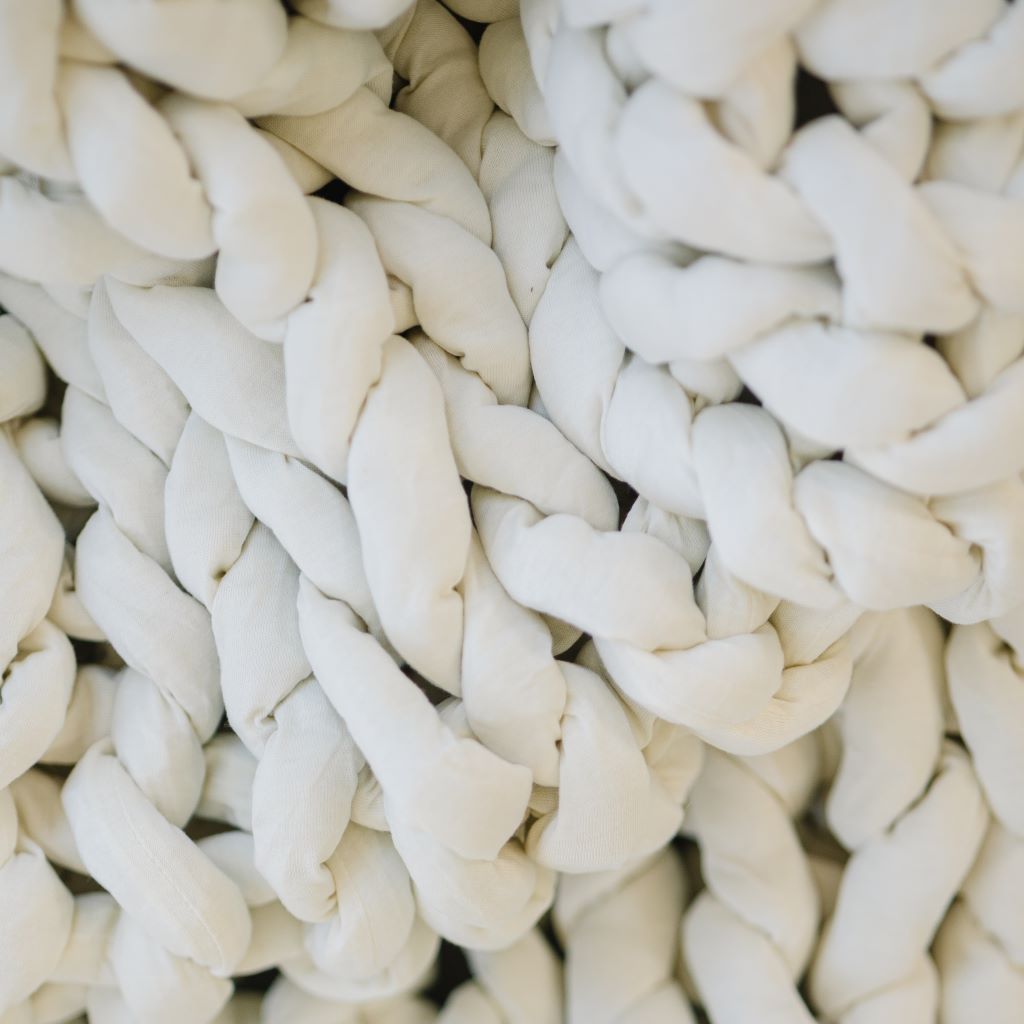 Close-up of thick, cream-colored yarn woven in chunky braids creates a soft, textured pattern typical of the Knit Weighted Blanket.