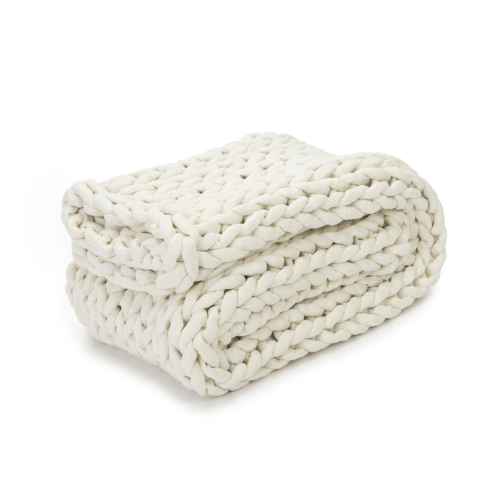 The Knit Weighted Blanket in cream features a thick, braided design and is folded neatly on a white background.