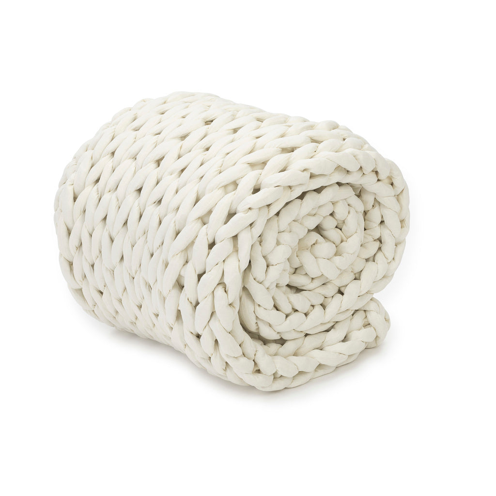 The Knit Weighted Blanket, featuring a chunky hand-knit white braided design, is rolled into a spiral and displayed on a white background.