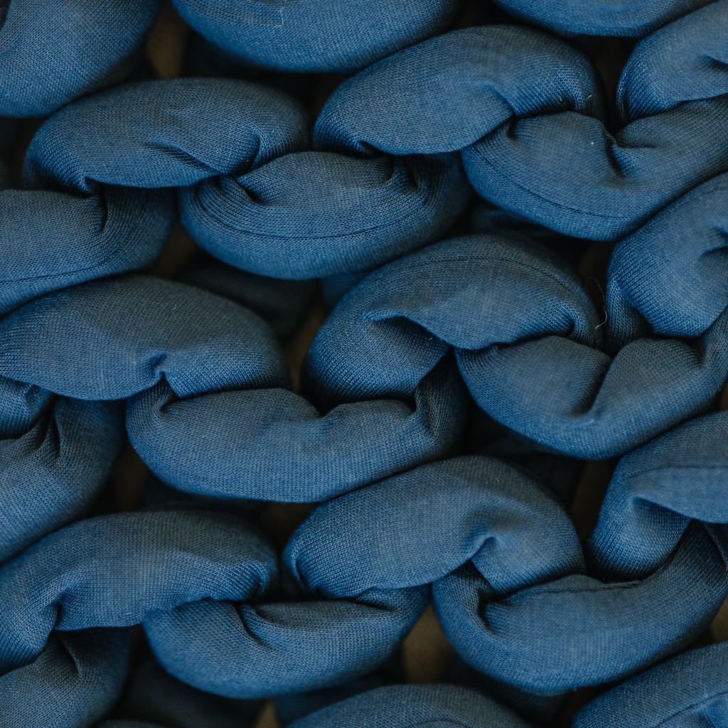 Close-up of thick, soft blue strands woven together in a chunky braid, showcasing the textured surface of the Knit Weighted Blanket.