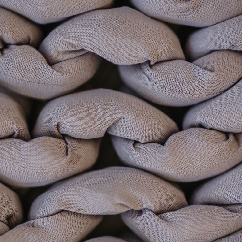 Close-up of chunky, beige strands tightly braided together, highlighting the textured and cozy appearance of the Knit Weighted Blanket.
