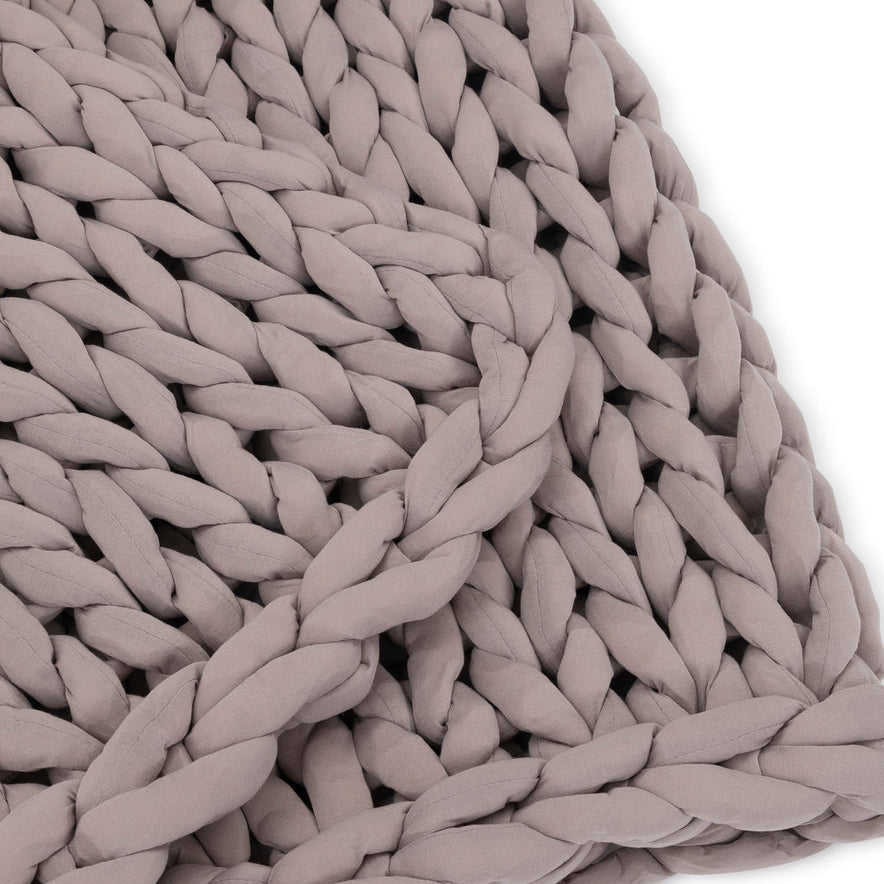 Close-up of the Knit Weighted Blanket in soft taupe, featuring chunky, braided strands that form a textured pattern with visible loops and braids, set against a white background.