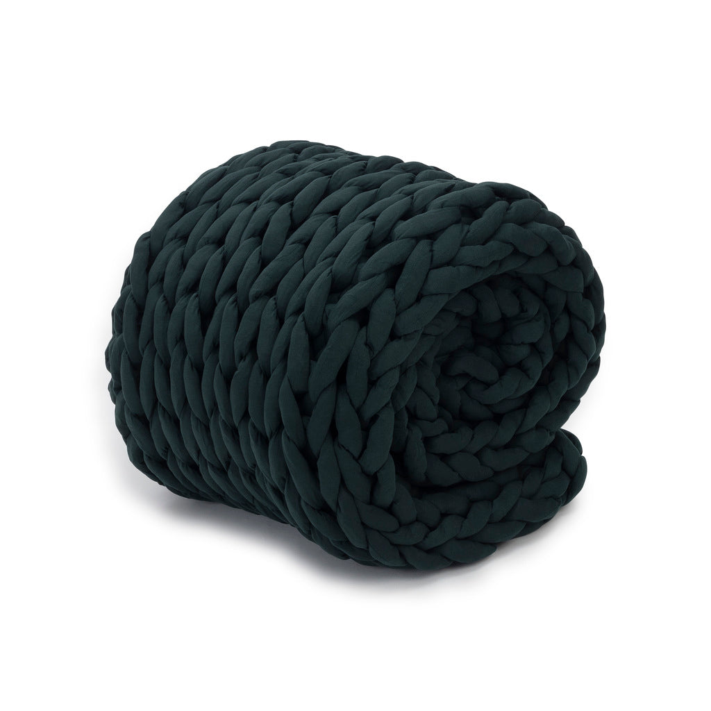 The Knit Weighted Blanket, in dark green, is rolled up to showcase its thick, chunky braided knit texture against a white background.