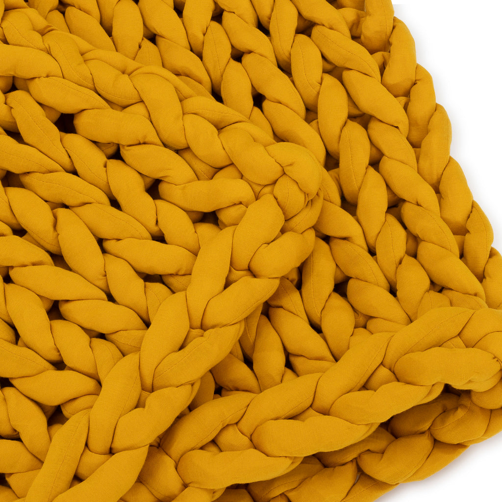 Close-up of the Knit Weighted Blanket in chunky, breathable knit, crafted from thick mustard yellow yarn with large interwoven stitches highlighting its soft, cozy texture.