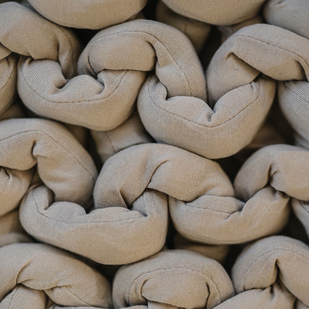 Close-up of thick beige strands woven in a chunky, braided pattern, creating a textured and interlocked surface on the Knit Weighted Blanket.