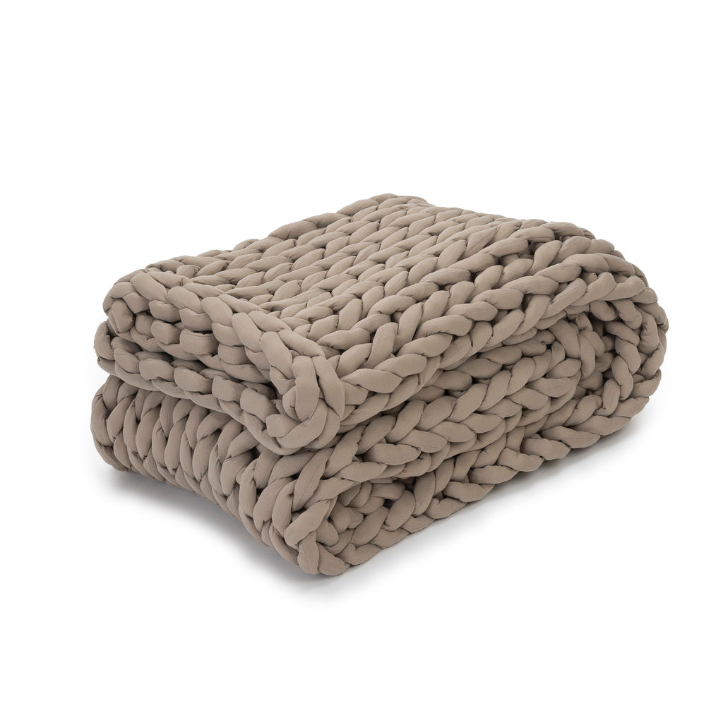 The Knit Weighted Blanket in taupe is neatly folded, highlighting its chunky braided texture and providing cozy comfort.