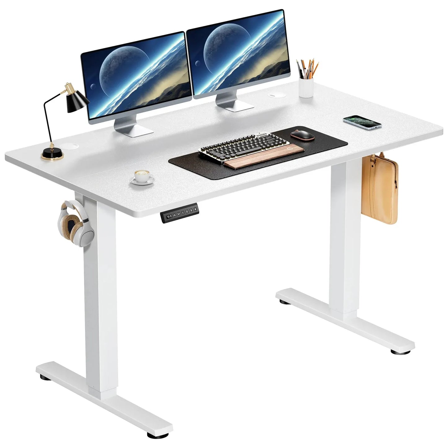 The JHK Electric Height Adjustable Standing Desk in white, 40x24 inches, features dual monitors showing planets, with a keyboard, mouse, and desk mat. A lamp, mug, stationery holder sit atop; headphones hang on one side and a pouch is attached on the other.