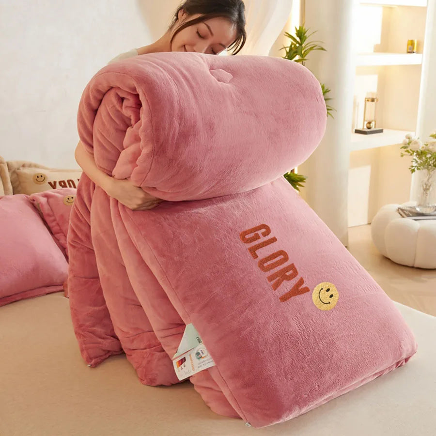 A person holds the KDJEIKZ Ultra Cozy Winter Weighted Blanket, featuring a rolled milk velvet comforter with GLORY and a smiley face. Bathed in soft, warm lighting with matching pink cushions, this elegant and thick winter blanket adds coziness to the scene.