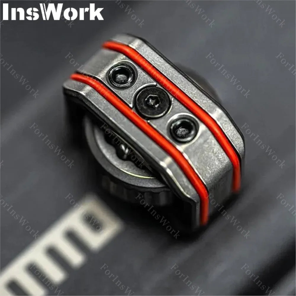 Close-up of the Ammo Cracker Unzip Roller Fidget Toy Stress Relief Slider EDC Tool, featuring a metallic component with three screws and two red bands, on a dark surface. The InsWork logo appears in the upper left corner.