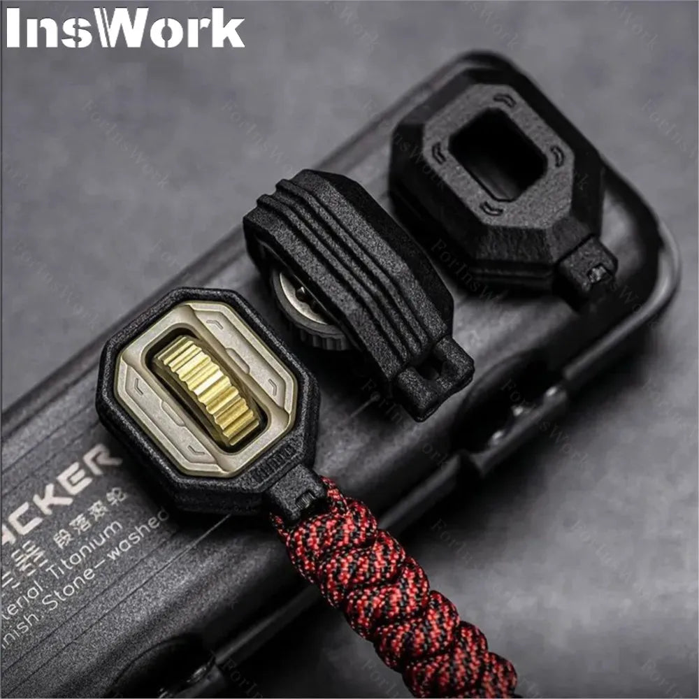 Close-up of the Ammo Cracker Unzip Roller Fidget Toy Stress Relief Slider EDC Tool in black and gold, with a red-black braided paracord. Features a textured dial, protective cover, and fidget function, attached to an object labeled TACKER.