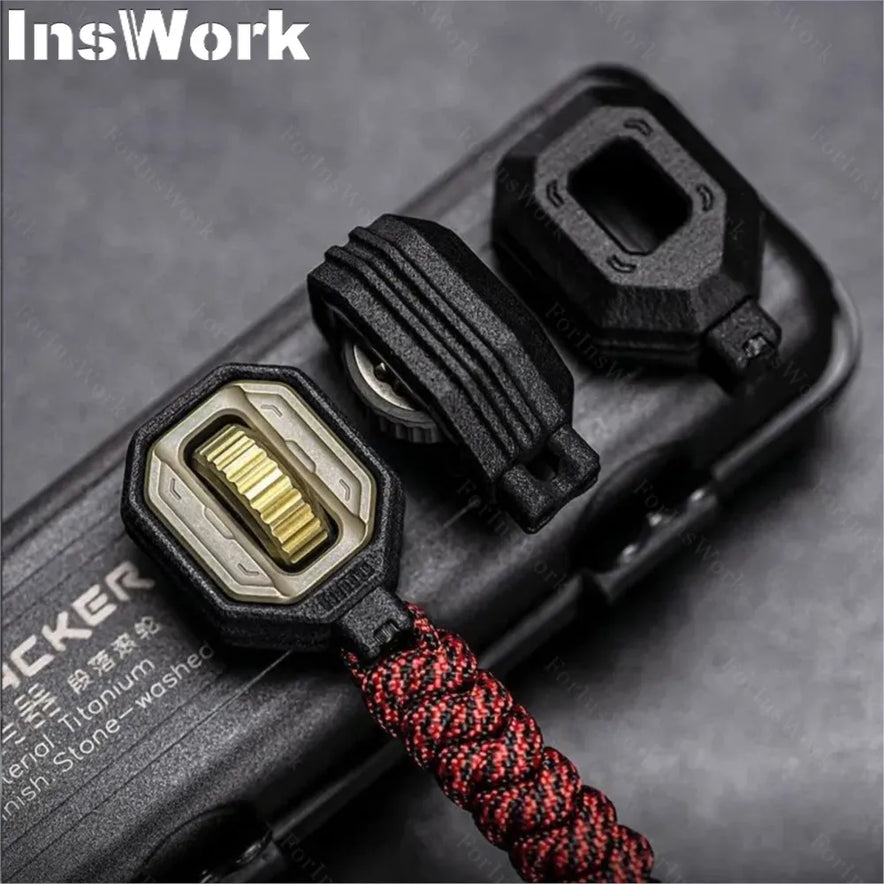 Close-up of the Ammo Cracker Unzip Roller Fidget Toy Stress Relief Slider EDC Tool in black and gold, with a red-black braided paracord. Features a textured dial, protective cover, and fidget function, attached to an object labeled TACKER.