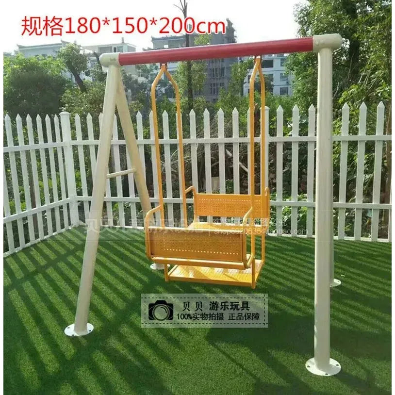 The Outdoor Steel Climbing Frame Swing, ideal for sensory integration training, features a yellow swing with a red crossbar on artificial grass, surrounded by trees and a white picket fence. Dimensions: 180*150*200 cm. A small round logo with Chinese text notes its childrens benefits.