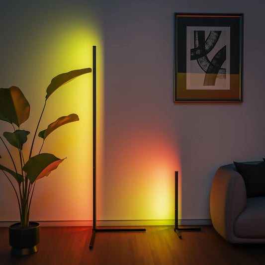 A modern living room features two minimalist LED lamps, including the Smart RGB Dream Color Floor Lamp LED Soft Eye Protection Dimmable APP Controlled Mood Lamp, a large potted plant, abstract wall art, and a gray sofa on wooden flooring—ideal for modern lighting.