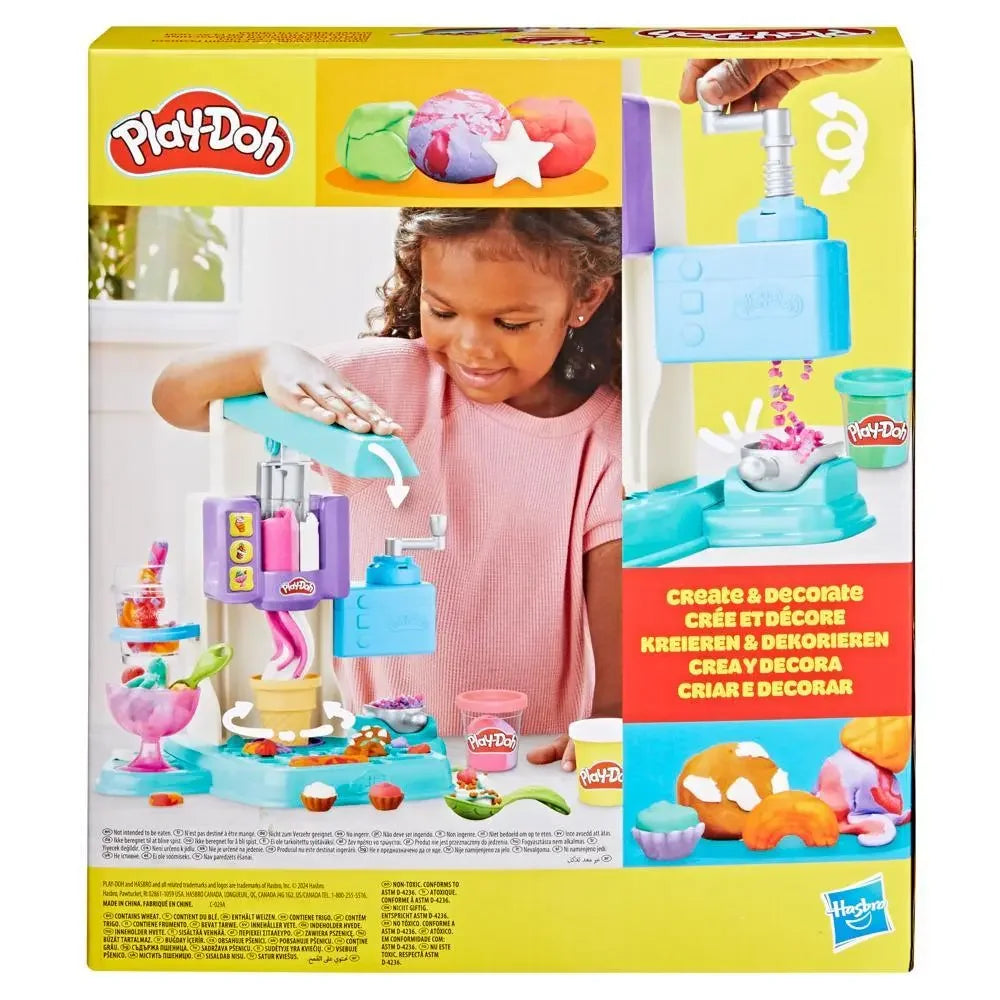 The image showcases the Hasbro Play Doh Rainbow Swirl Ice Cream Playset package. A smiling child enjoys vibrant creations with tools around her. The packaging features prominent branding and multilingual instructions, promising endless imaginative fun.