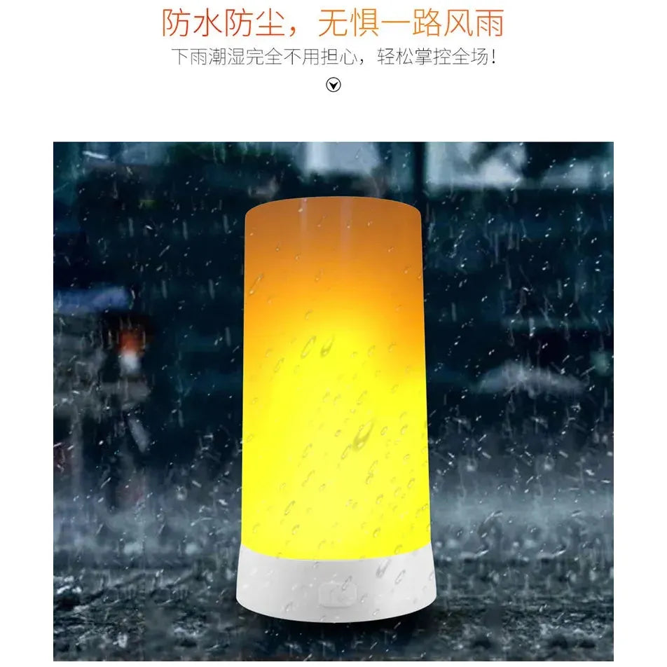 The Simulated Flame LED Night Light, shaped like a cylinder, glows yellow in the rain. Raindrops enhance its realistic flame effect, while elegant Chinese text above hints at its versatile use in different settings.
