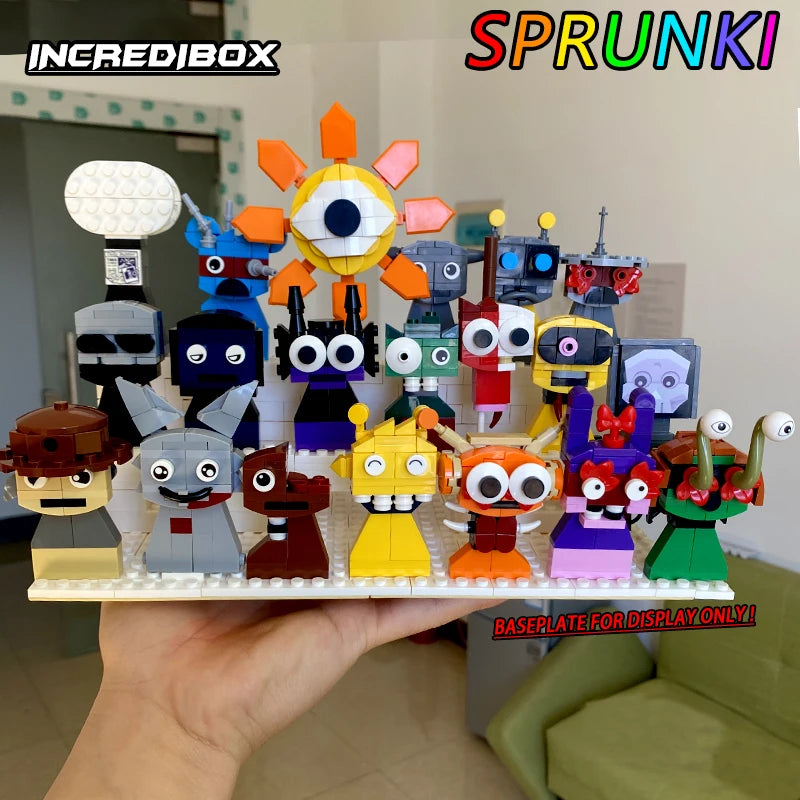 A hand shows colorful LEGO-style creatures from the New Moc Incredibox Sprunki Building Blocks Set. Each has a unique face and expression. Living room in background. Text: INCRDIBOX, SPRUNK!, BASEPLATE FOR DISPLAY ONLY!.