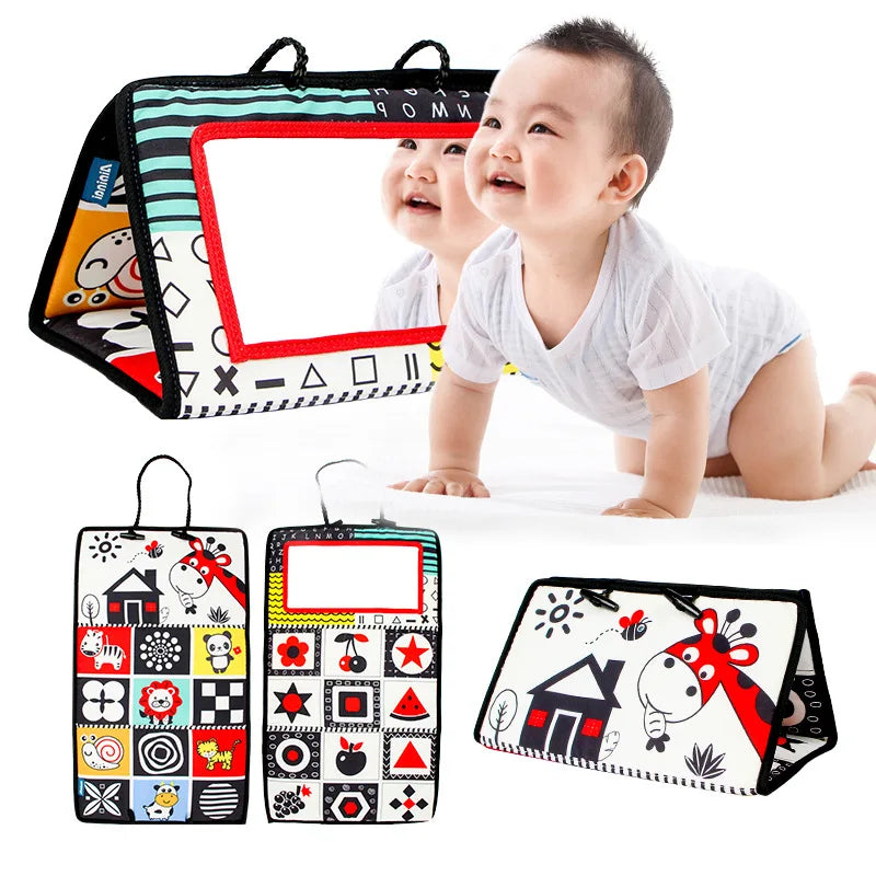 A baby on a white surface explores the Crinkle Cloth Book Mirror Toy, designed for sensory exploration with prints like a dog, house, sun, and stars. The triangular mirror offers visual stimulation with its vibrant patterns—two views shown. Suitable for newborns 0-3 months.