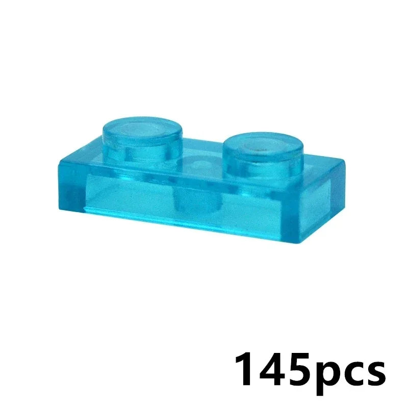A 1x2 transparent blue brick from the MOC Transparent Bulk Brick Set—compatible with Lego—is shown on a white background, ideal for adding to your clear building block collection. 145pcs is displayed in black in the bottom right corner.