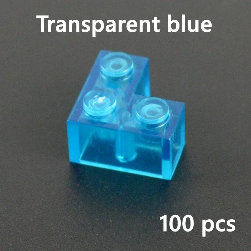 A blue L MOC Transparent Bulk Brick is shown on a dark surface. Top text: MOC Transparent Bulk Brick (blue L). Bottom text: 100 pcs, perfect for your Lego compatible collection.