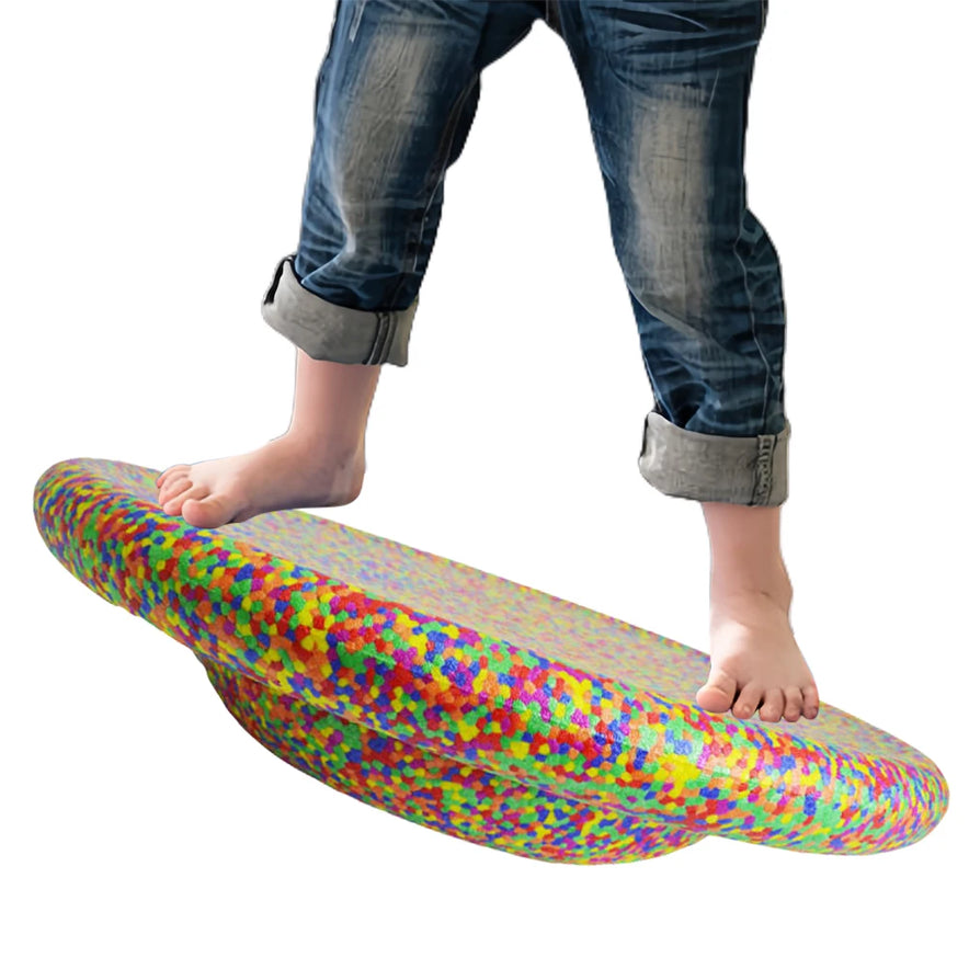 A child stands barefoot on a Stability Board Non-slip Balance Stepping Stones Flower Shape, wearing rolled-up jeans; this unisex rotating balance exerciser is ideal for home or school, shown isolated on a white background.