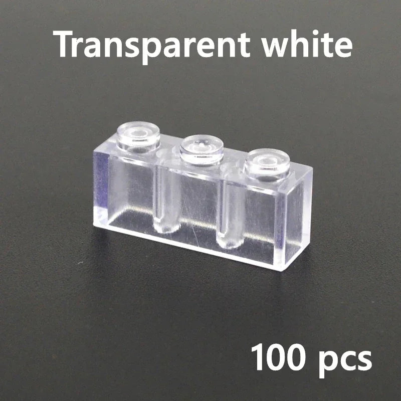 A transparent 1x3 LEGO-compatible brick from the MOC Transparent Bulk Brick Set is shown on a dark surface. Text above says Transparent Bulk Brick and below reads 100 pcs, perfect for any building block collection.